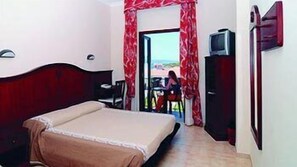 A bedroom with a bed, a TV, and a view of the outside. - Hotel Stella Del Sud (Calasetta)