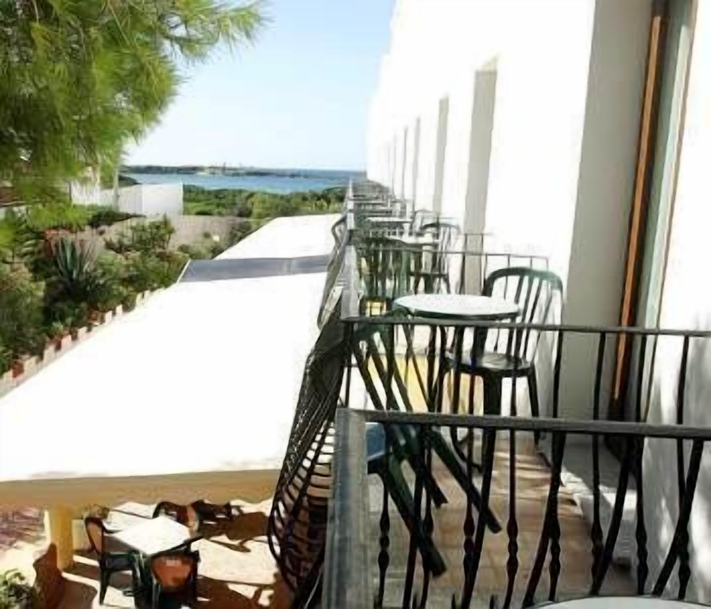 Un balcon avec vue sur la mer, aménagé avec des tables et des chaises.