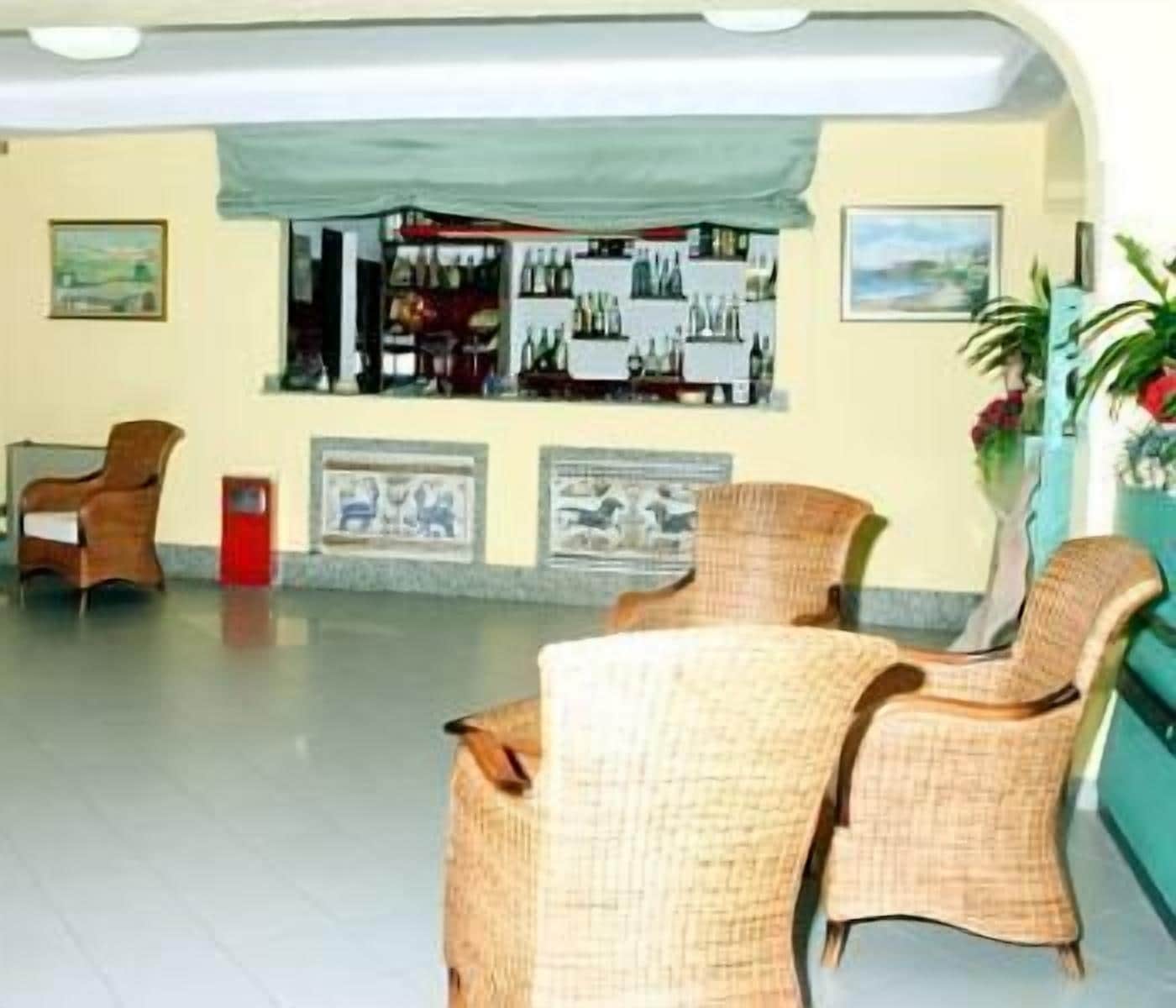Un hall d'entrée avec des fauteuils en osier, un comptoir de réception et des tableaux encadrés accrochés au mur.
