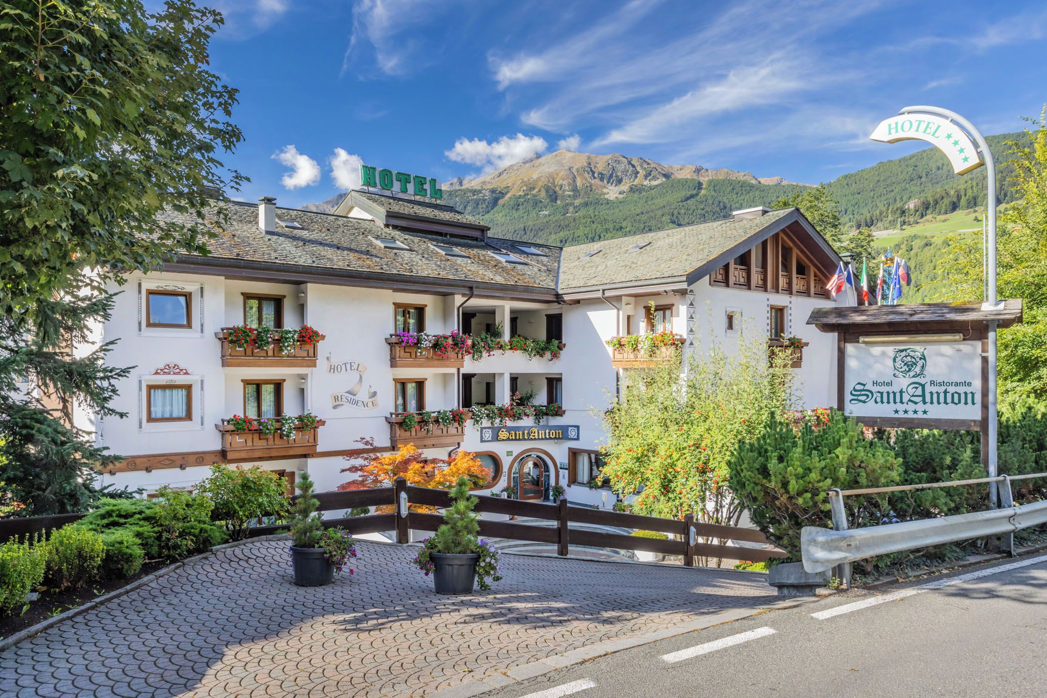 A hotel with a sign indicating it is a residence, surrounded by lush greenery and a mountainous backdrop.