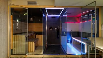 Un baño moderno con ducha acristalada, banca de madera y un inodoro a la vista.