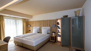 Ein modernes Hotelzimmer mit einem großen Bett, einem Schreibtisch und einem Bücherregal.