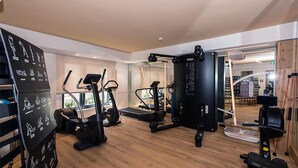 A gym with cardio machines, weightlifting equipment, and a mirrored wall. - Citta Trüffel Hotel (Wiesbaden)