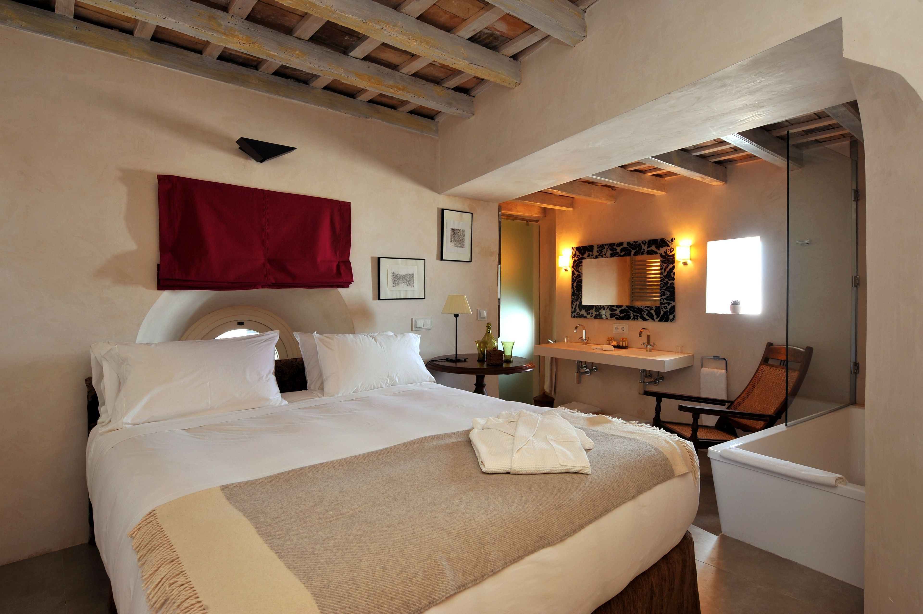 A hotel room with a large bed, a bathroom with a bathtub, and a mirror.