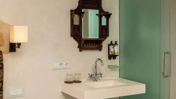 A modern bathroom with a white sink, a mirror, and a green shower door.