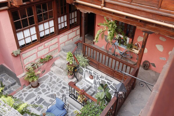 A courtyard with a stone floor, potted plants, a blue chair, and a wooden railing. - Hotel Rural Fonda Central (Adeje)