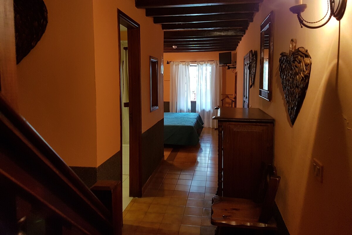 A hallway with a staircase, a bed, and a desk.