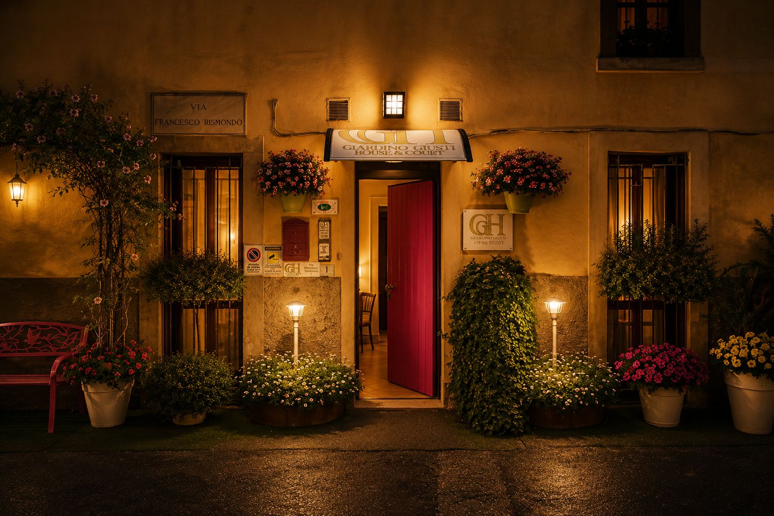 Entrada de un hotel con puerta roja, plantas en macetas y un cartel que dice 'Giardino Giusti House & Court'.