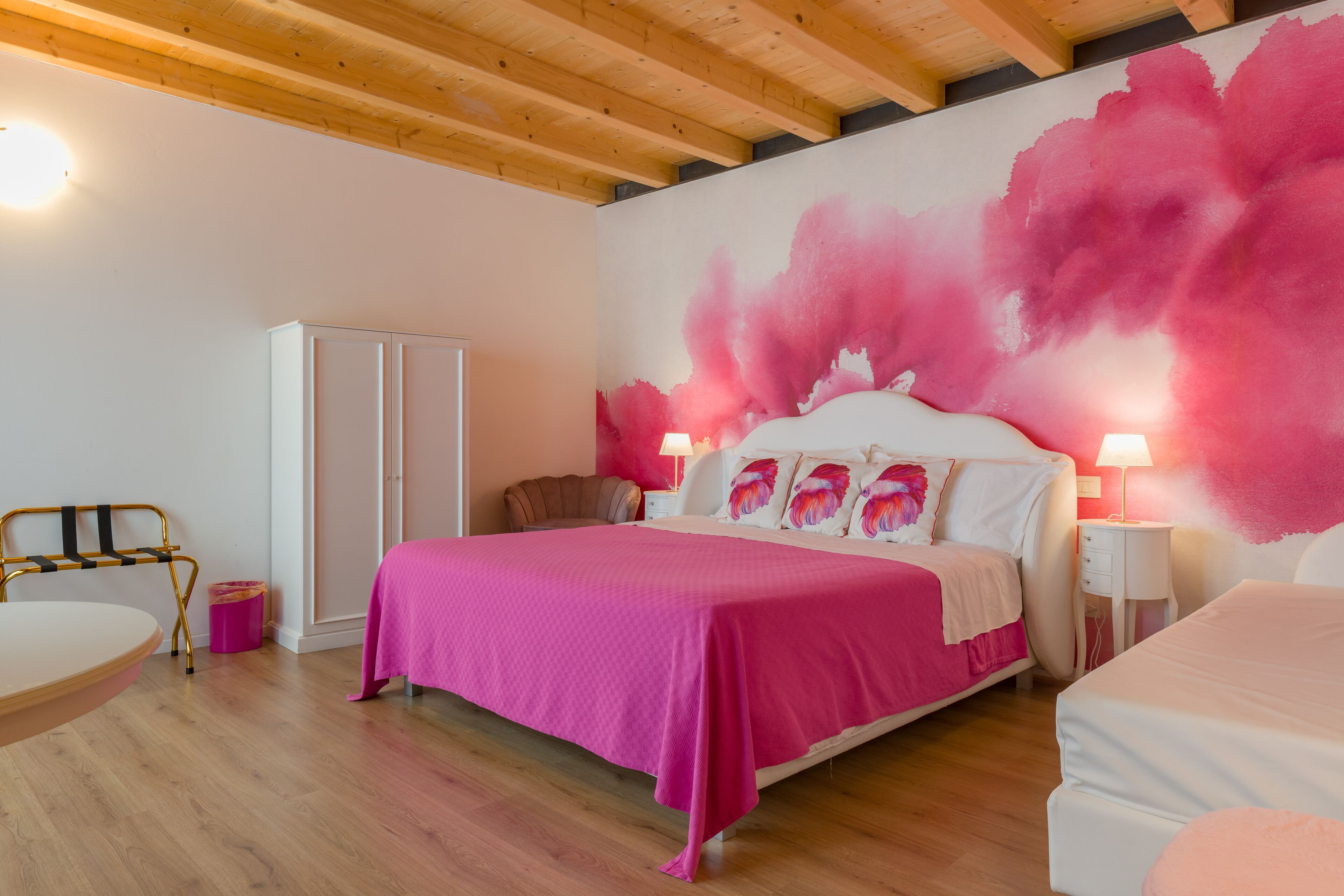 Un dormitorio con una cama grande, techo de madera y pintura rosa en la pared.