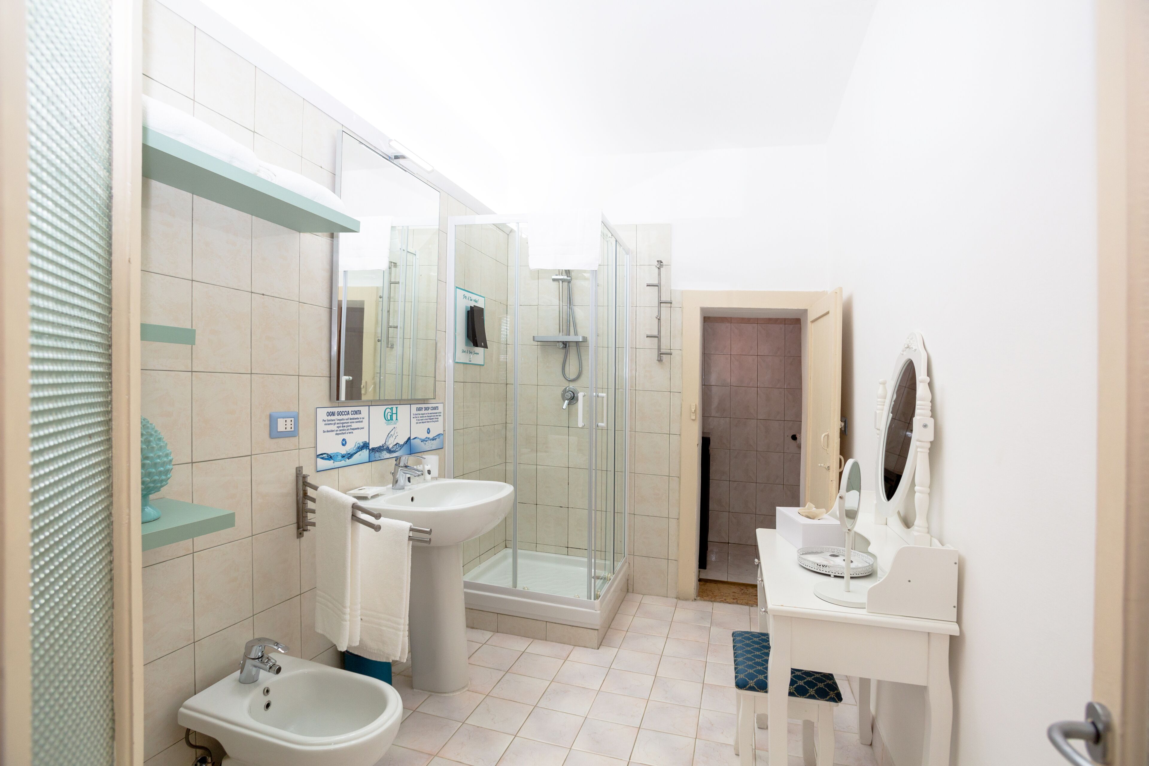 A modern bathroom with a glass-enclosed shower, a sink, a bidet, and a vanity with a mirror.