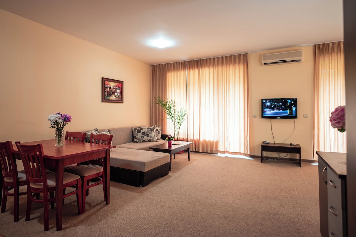 A living room with a dining table, sofa, and television.