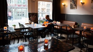 A cozy restaurant with leather booths, tables with candles, and a view of the city. - La Boheme (Amsterdam)