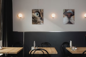 A restaurant interior with wooden tables, black chairs, and wall-mounted light fixtures. - La Boheme (Amsterdam)