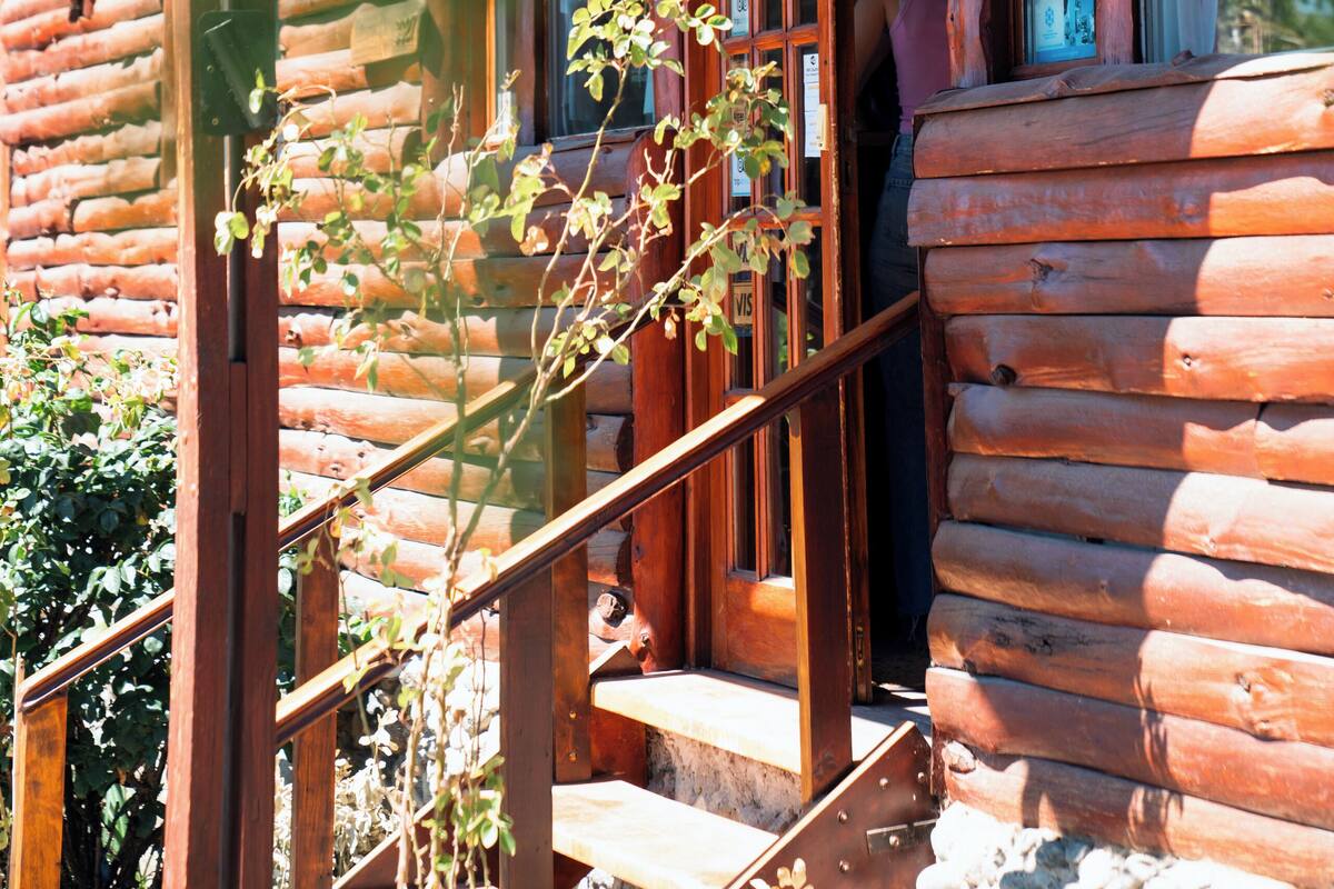 Une cabane en bois avec une véranda, un escalier et une fenêtre avec des rideaux.