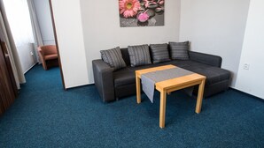 Una sala de estar moderna con un sofá gris oscuro, cojines estampados, una mesa de centro de madera y un cuadro de flores en la pared.