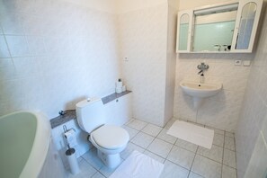 A small, clean bathroom with a toilet, sink, and bathtub. - A-Sport Hotel (Brno)