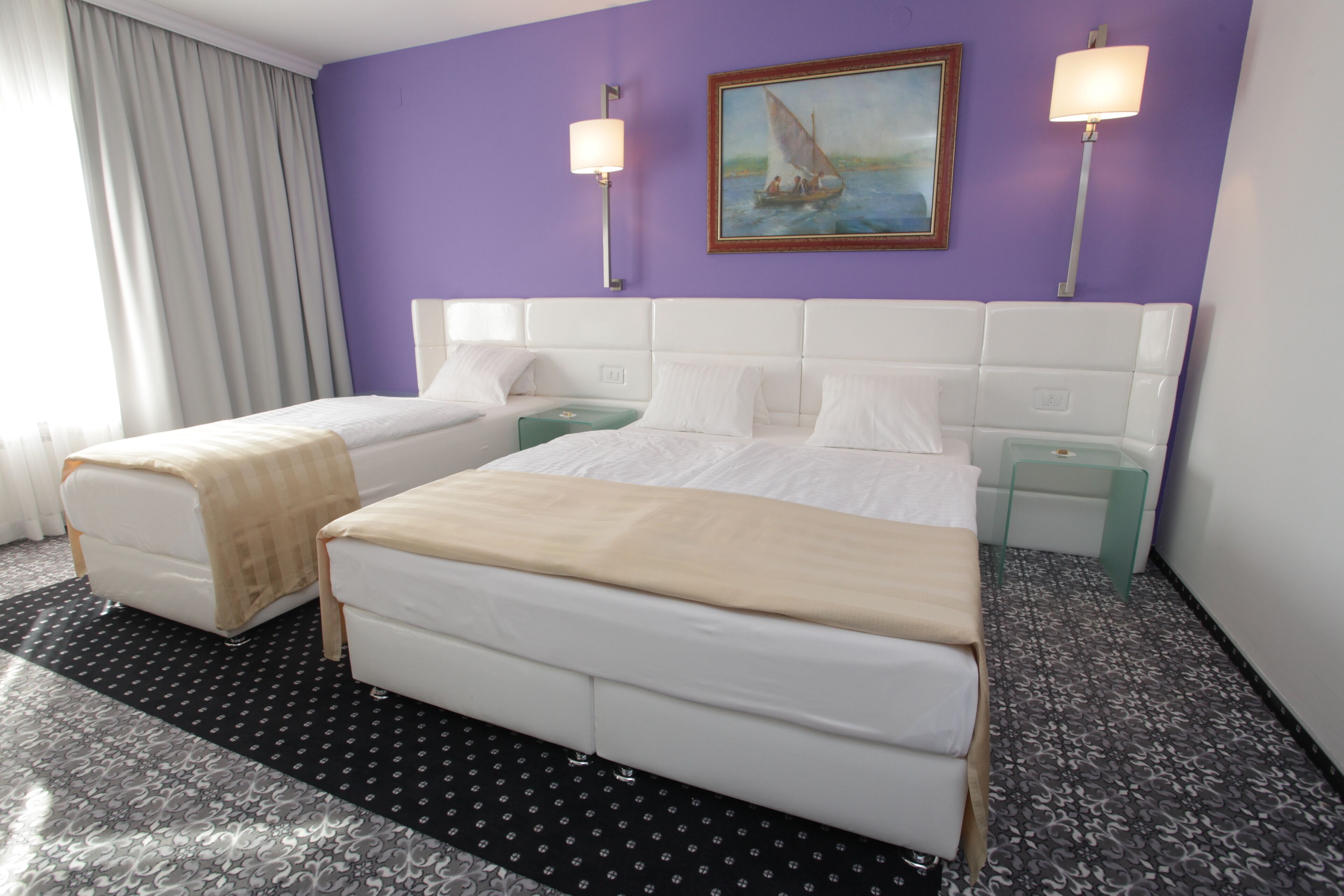 Une chambre d’hôtel avec deux lits, un tableau au mur et deux lampes de chevet.