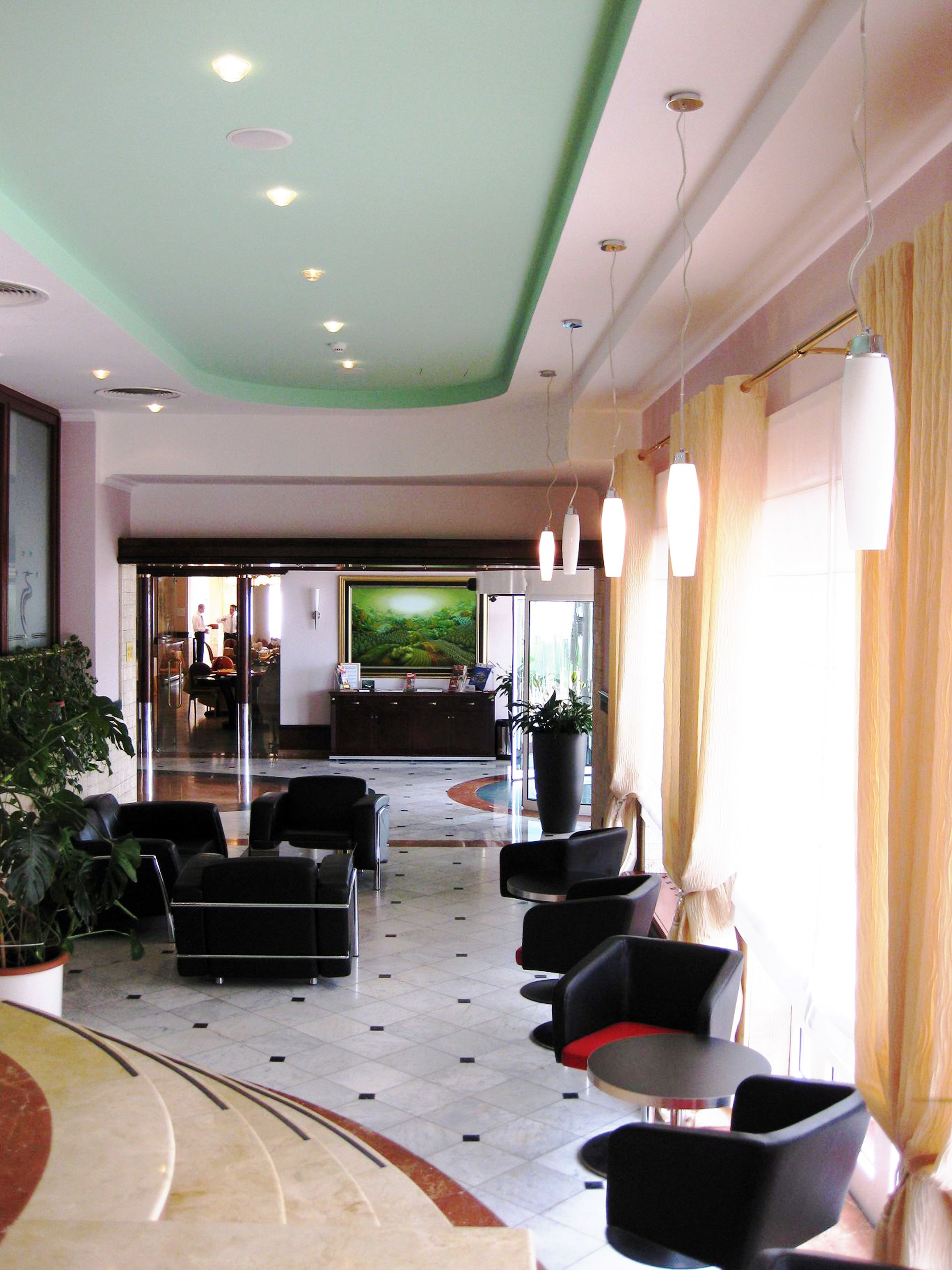 A hotel lobby with a reception desk, seating area, and a large TV screen.
