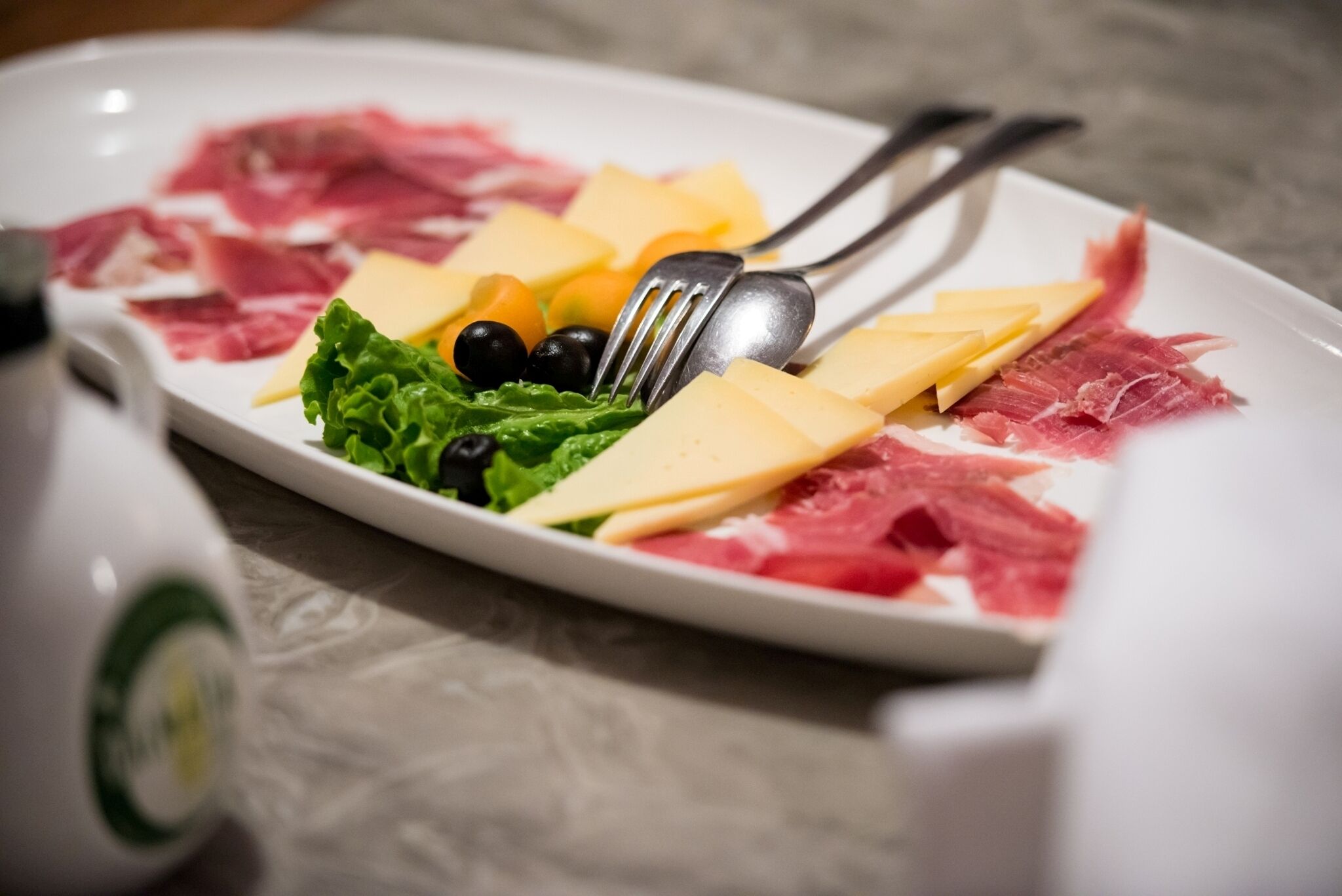 A plate of food with various items including cheese, meat, and greens.