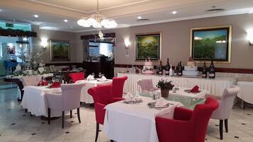 Un restaurante con mesas dispuestas para comer, sillas rojas y un candelabro.