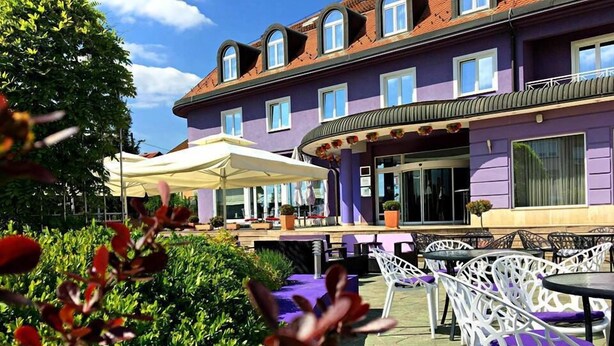Un hôtel doté d’une terrasse extérieure, d’un patio couvert et d’une façade violette.