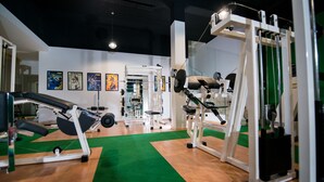 Une salle de sport équipée de matériel d’exercice, de tapis verts et d’œuvres d’art accrochées aux murs.