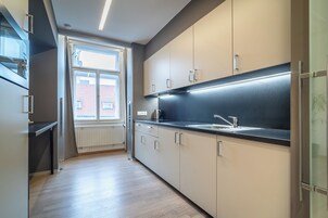 Uma cozinha moderna com armários claros, bancada preta e uma janela que permite a entrada de luz natural.