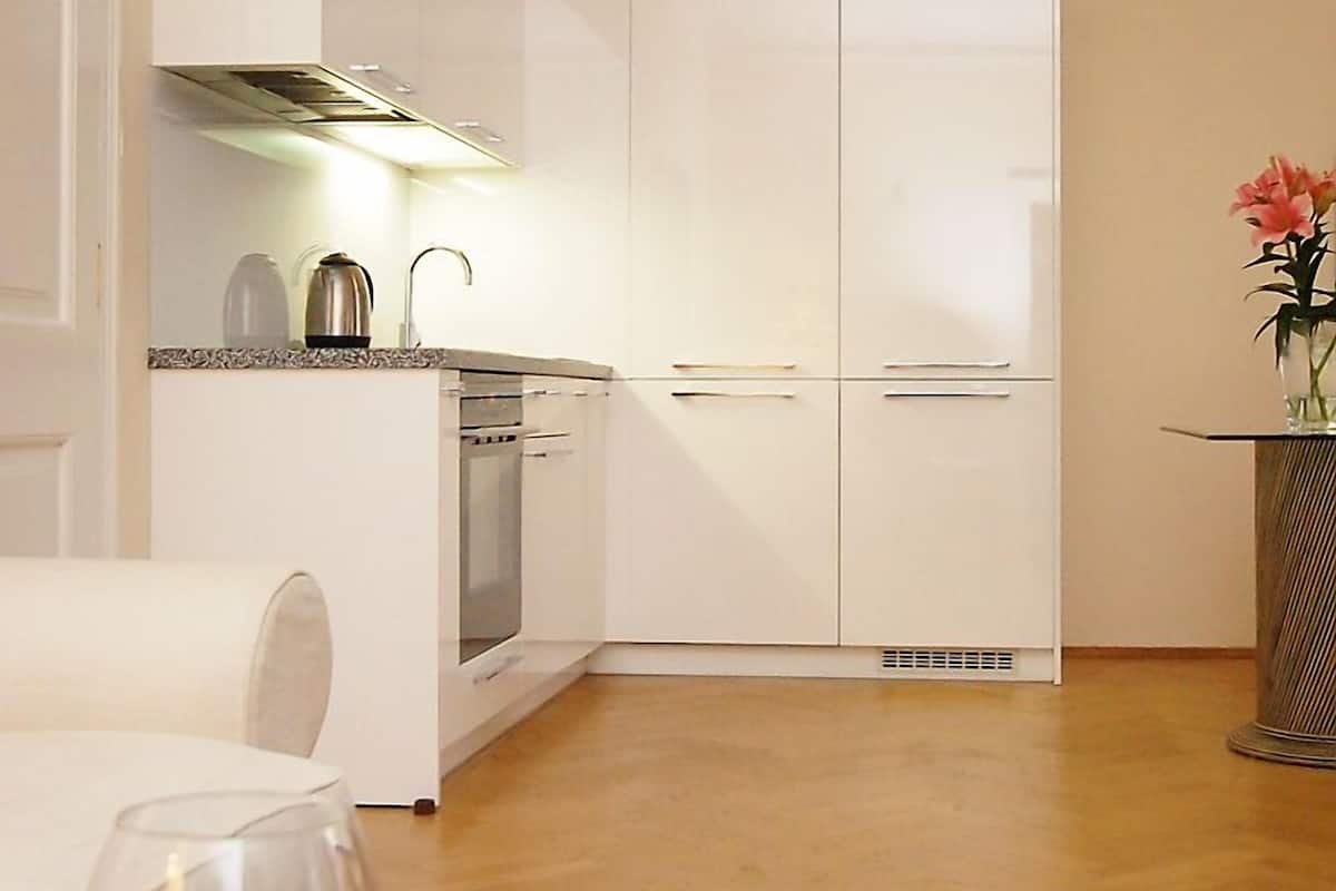 Una cucina moderna con mobili bianchi, forno integrato e macchina per il caffè.