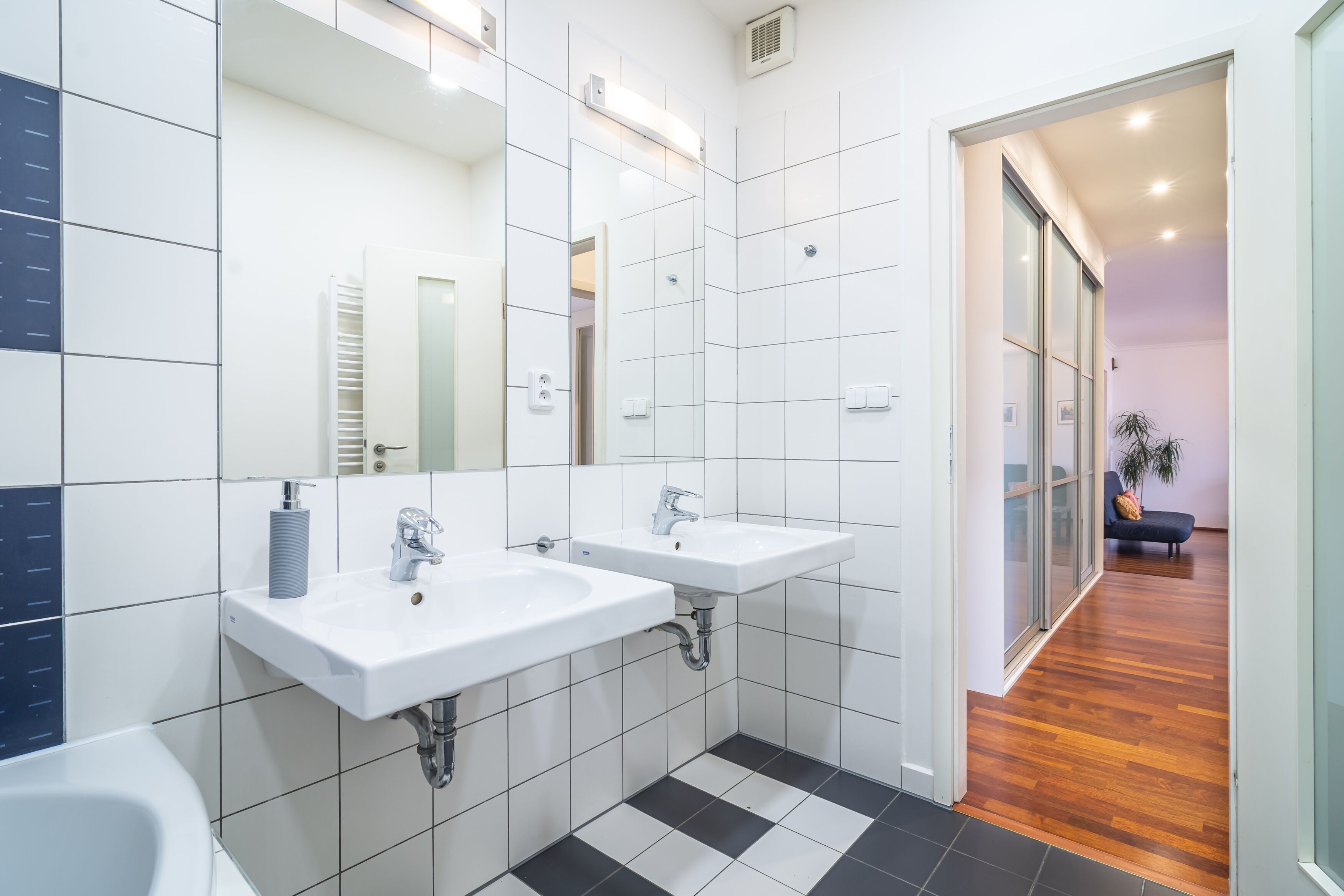 Un baño moderno con dos lavamanos, un espejo grande y una zona de ducha.