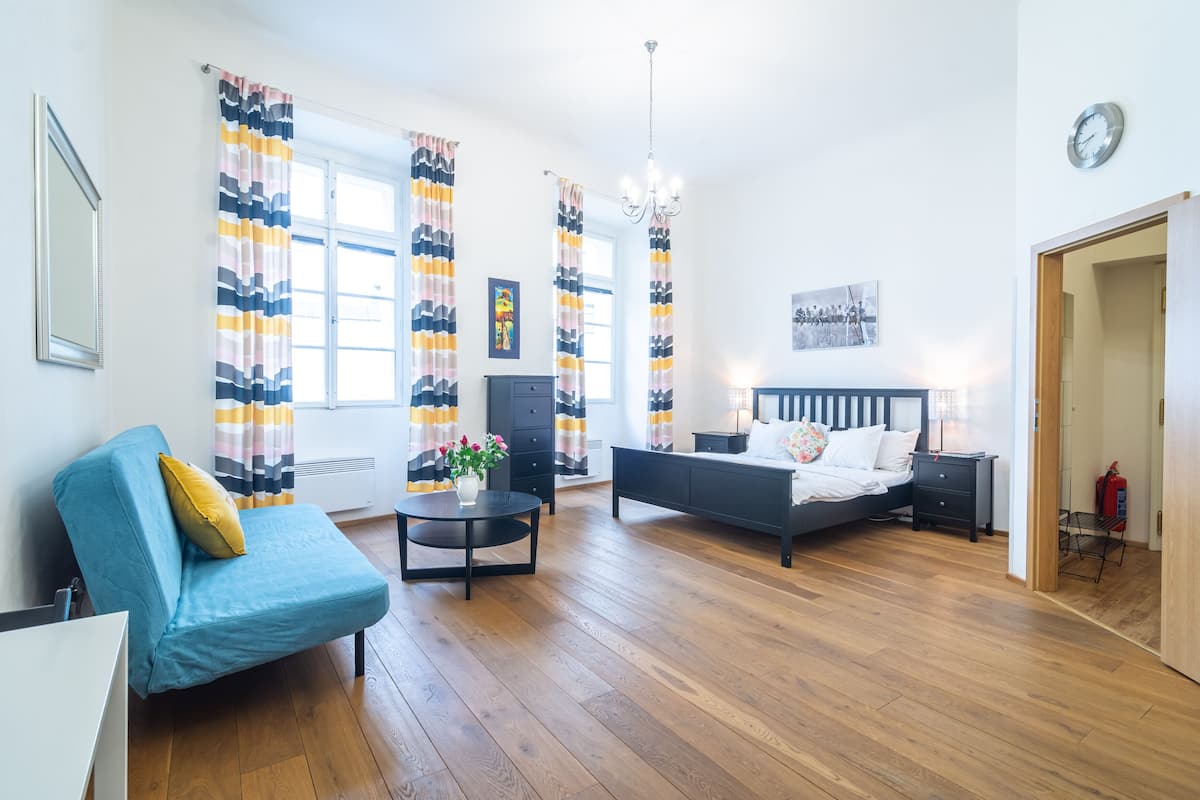 Una camera da letto moderna con un letto, un divano blu, un tavolino con fiori e un comodino.