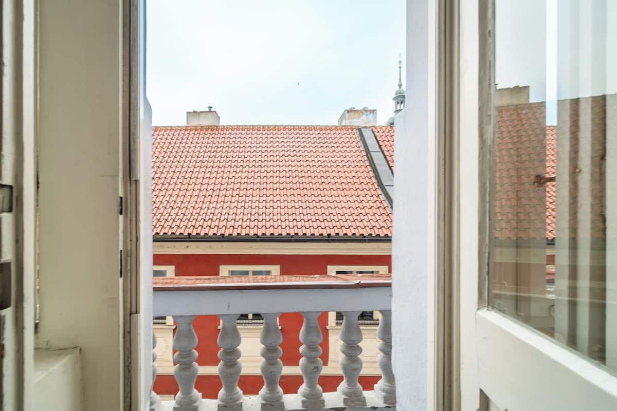 Vista da un balcone con tetto in tegole rosse e balaustra bianca.
