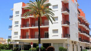 A multi-story hotel with balconies, a palm tree in front, and a clear blue sky. - Hotel Caribe (Rota)