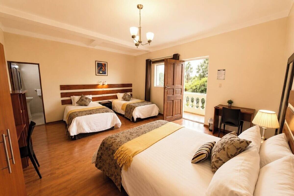 Habitació d'hotel amb un llit gran, dos llits més petits, un escriptori i una cadira.