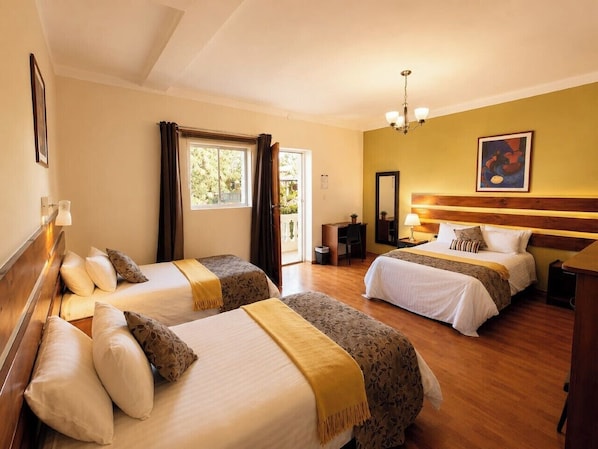 Habitación de hotel con dos camas, un escritorio, una silla, un espejo y una ventana con cortinas.