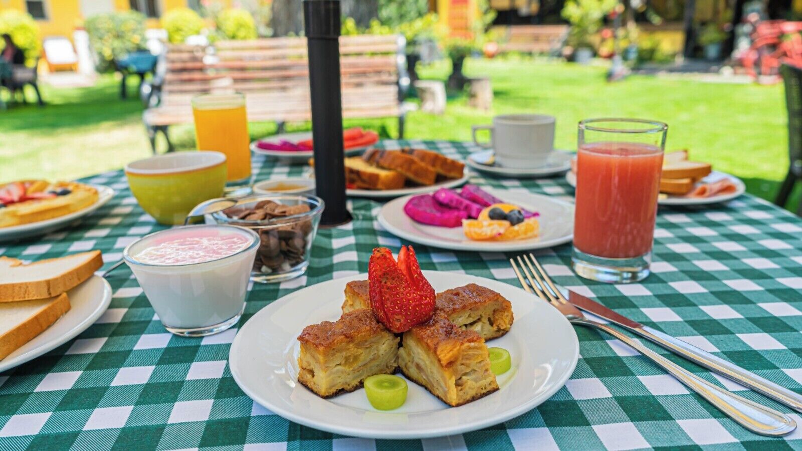 Et bord dækket med morgenmad, inklusive ristet brød, en frugtsalat, en drik og en dessert.