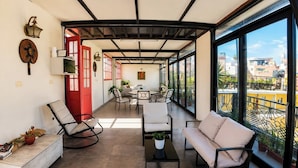 A spacious balcony with seating, a red door, and a view of the cityscape. - Casa de Avila Hotel (Arequipa)