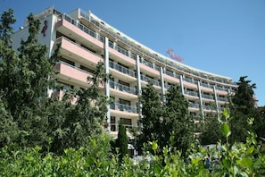 A multi-story hotel with balconies, surrounded by greenery.