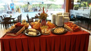 A buffet table with various food items and a vase of flowers. - Flamingo (Nessebar)