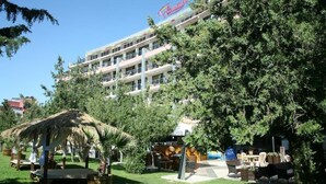 A hotel with a multi-story structure, outdoor seating area, and lush greenery. - Flamingo (Nessebar)