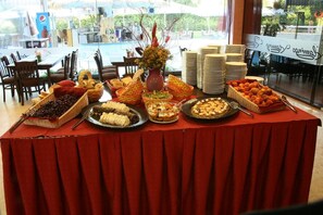 Una mesa de buffet con diversos alimentos y una pila de platos.