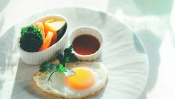 A plate with a sunny side-up egg, a bowl of mixed vegetables, and a small cup of sauce.