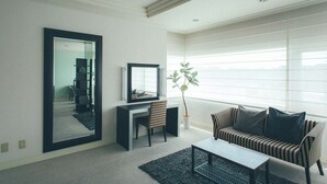 Uma sala de estar moderna com um espelho grande, uma escrivaninha, um sofá listrado e um vaso com planta.
