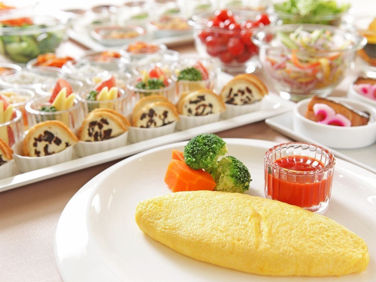 A plate with an omelette, broccoli, and carrot slices, accompanied by a glass of ketchup.