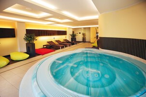 Un moderno spa con una bañera de hidromasaje grande, sillones reclinables y una camilla de masaje.