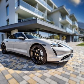 A modern building with a paved entrance and a parked sports car.