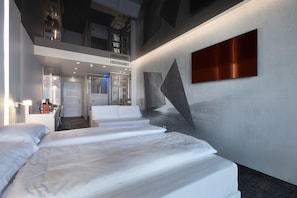 A modern hotel room with a large bed, a seating area, and a view of the sky. - Wellness Hotel Casa Barca - Adults Only (Malcesine)