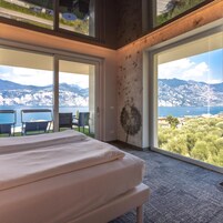 Un dormitorio con cama, ventanas amplias y vistas a un paisaje montañoso.