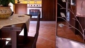 A kitchen with wooden cabinets, a stove, and a dining table with chairs. - Mamma Maria (Taormina)