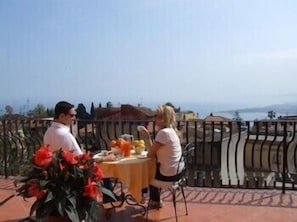 Una coppia cena a un tavolo con vista sul mare.
