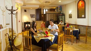 A dining area with a table set for two, a fireplace, and a stained glass window. - Belle Ville (Plovdiv)
